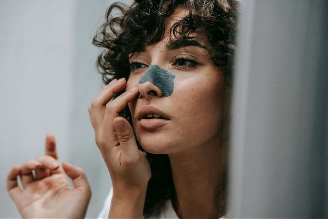 woman applying a nose strip to remove sebaceous filaments.