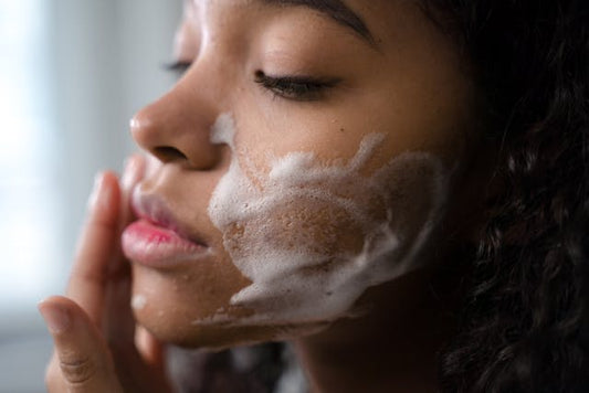 A woman cleaning her face with a facial cleanser