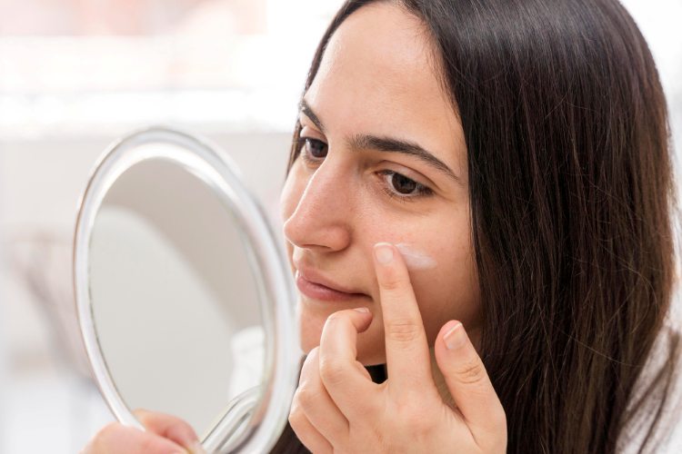 A woman applying barrier-repair moisturiser on her face
