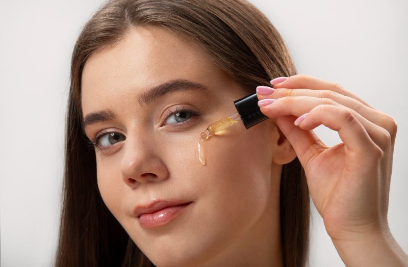 A girl applying a retinaldehyde serum on her face