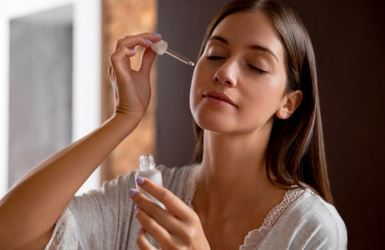 A woman applying retinaldehyde-infused serum to fight fine lines