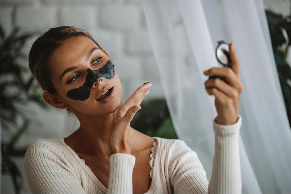 A woman using a clay mask to get rid of blackheads on her nose