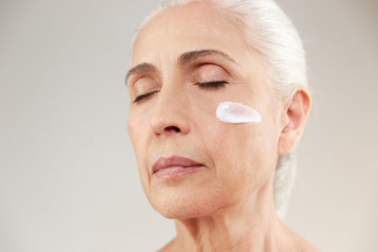 An aged woman with a stroke of vitamin A cream on her face