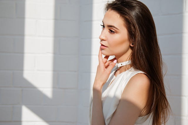 A woman with beautiful skin is standing in the beam of sunlight with her hair open