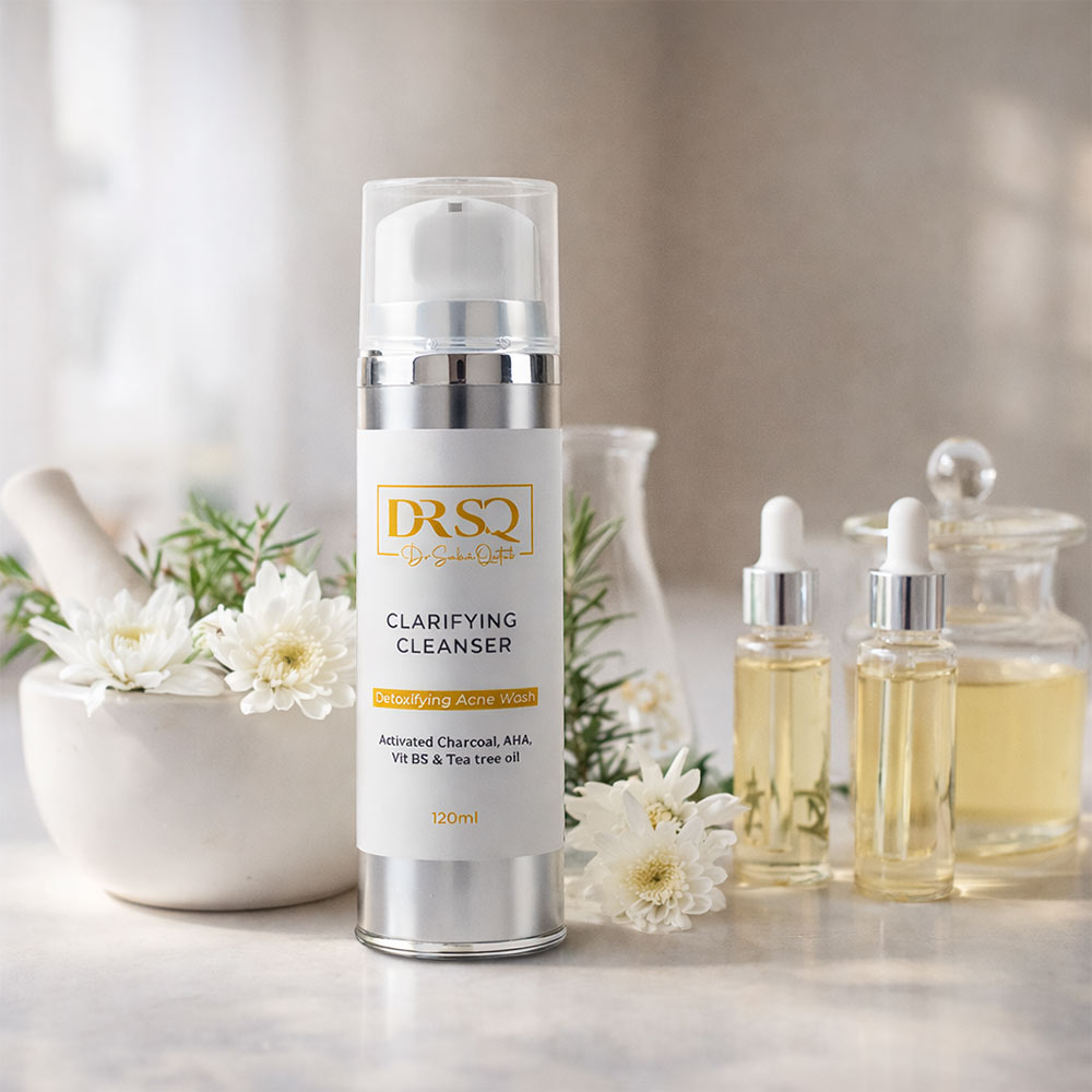 Clarifying Cleanser bottle displayed with glass serum bottles & white flowers